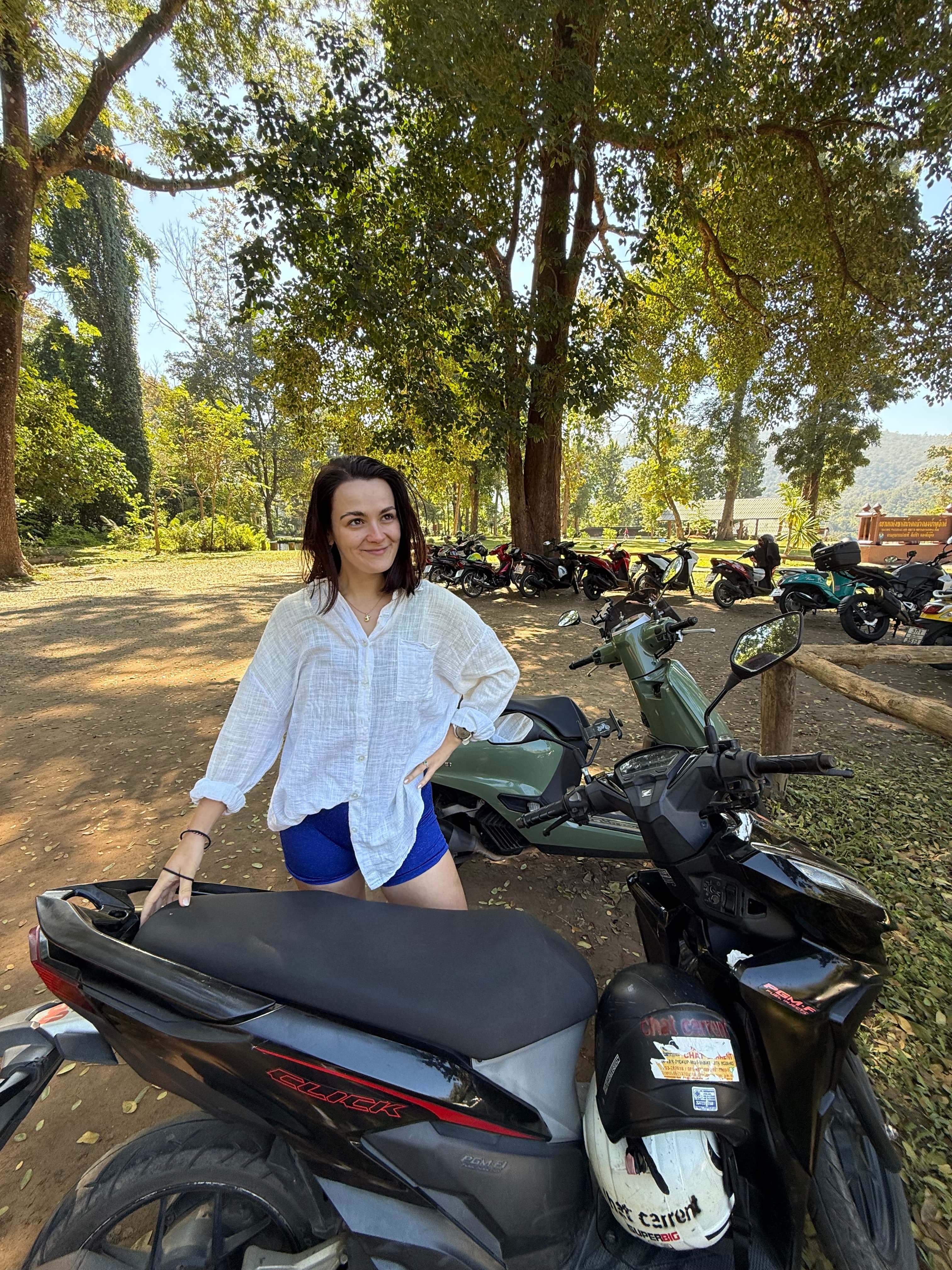 Tamara sitting on a scooter surrounded by trees
